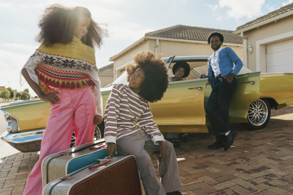 Happy family standing beside car with packed bags, ready to move into their new home after completing the Fearless Homebuyer Course